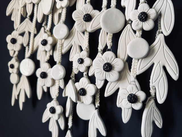White floral ceramic discs with black centers on a dark background