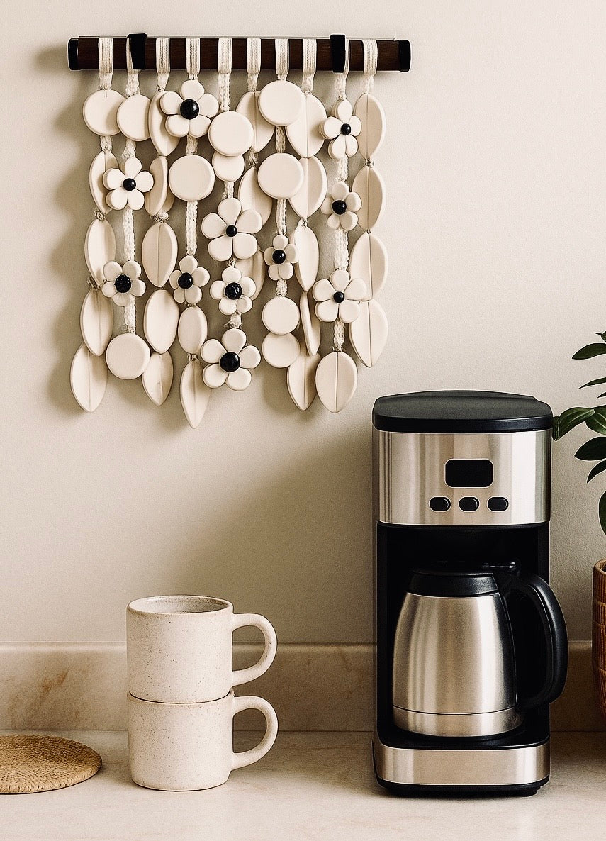 Coffee maker and mugs on a counter with decorative wall art above