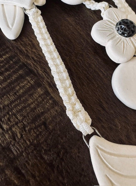 Close-up of a decorative item with white floral design on a dark brown surface