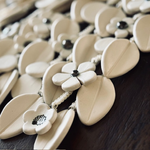 Close-up of a wall hanging with white floral pendants on a dark surface