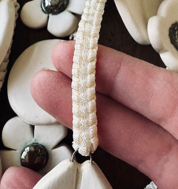 Close-up of a hand holding a beaded earring with a floral background.