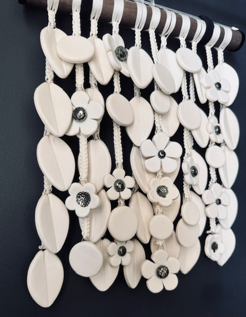 Decorative wall hanging with white floral and circular patterns on a dark background