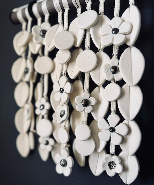 White floral wall hanging with black centers on a dark background