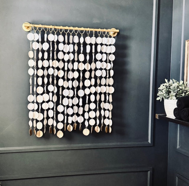 Decorative wall hanging with circular elements on a dark gray wall.