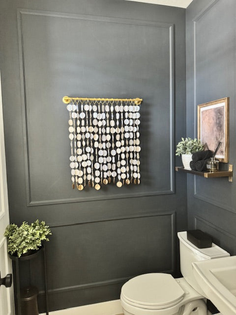 Bathroom with dark paneled walls, decorative wall art, and a toilet.