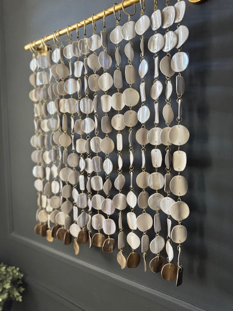 Decorative beaded curtain with gold accents on a gray wall