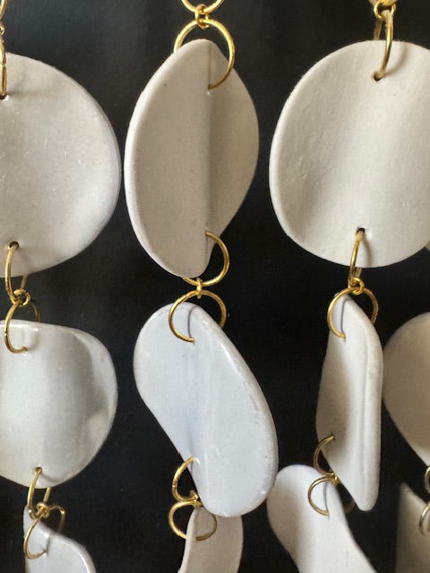 White earrings with gold hooks on a black background