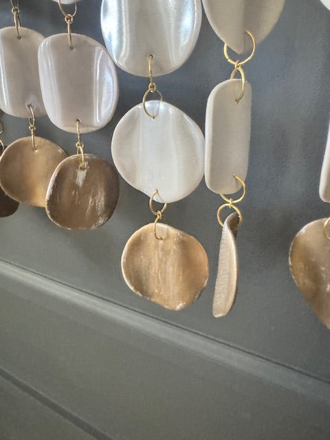 close up view of white and gold wall hanging on a black background