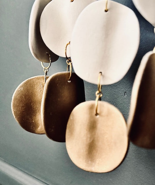 Gold and white ceramic discs hanging against a gray background